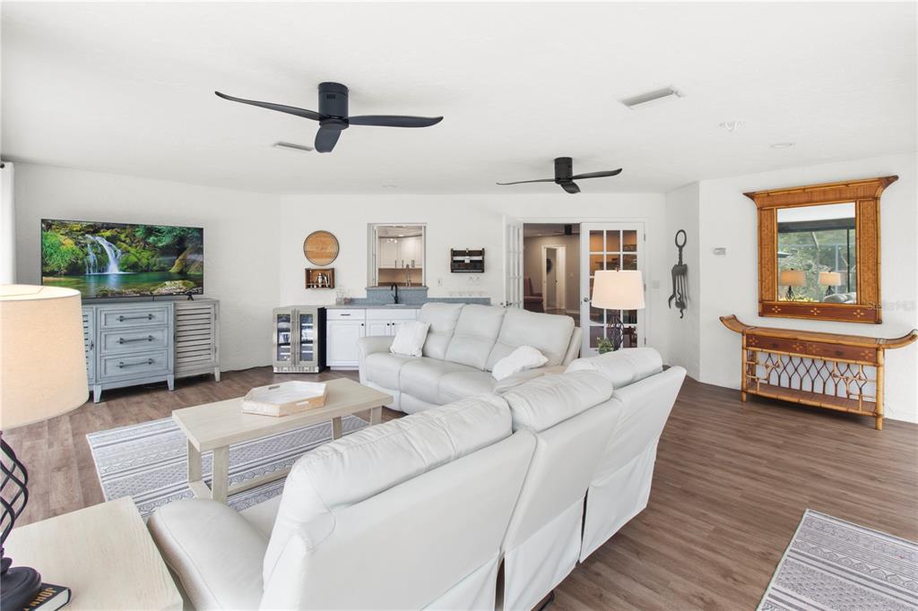 A living room features white sofas, a television, a wet bar, and two ceiling fans — 1279 CORNISH COURT, SARASOTA, FL