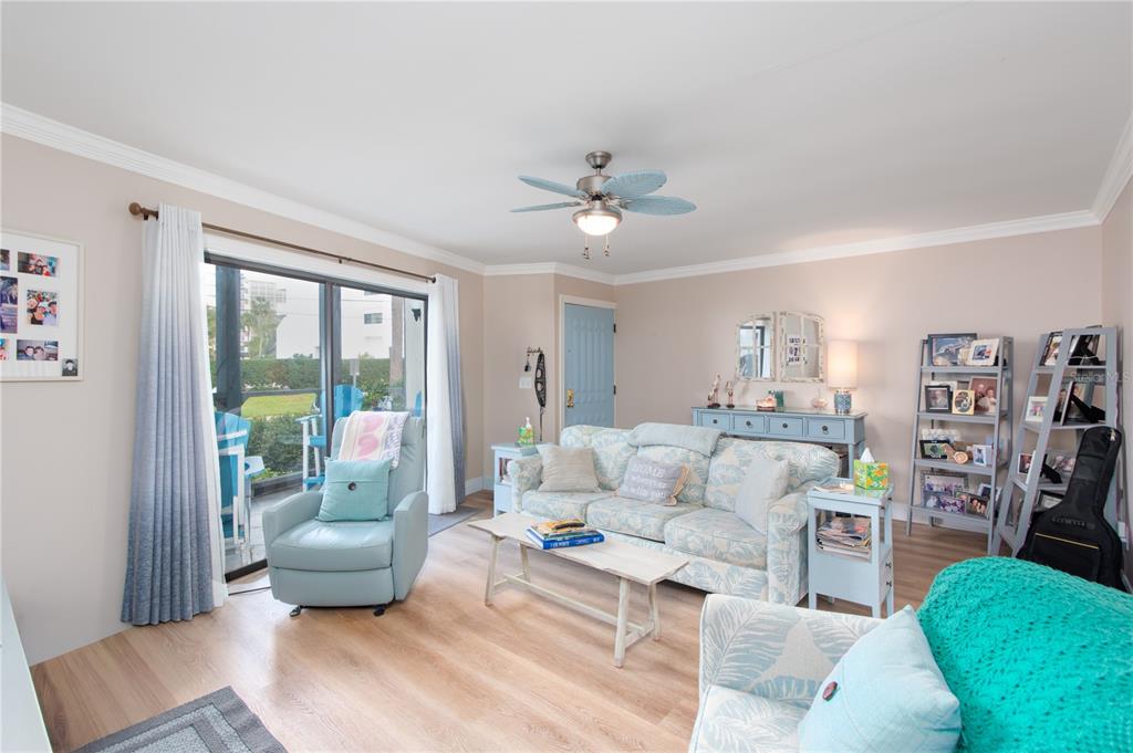 A living room features light wood flooring, a floral sofa, and a blue recliner — 15 TURNER STREET UNIT 4, CLEARWATER, FL