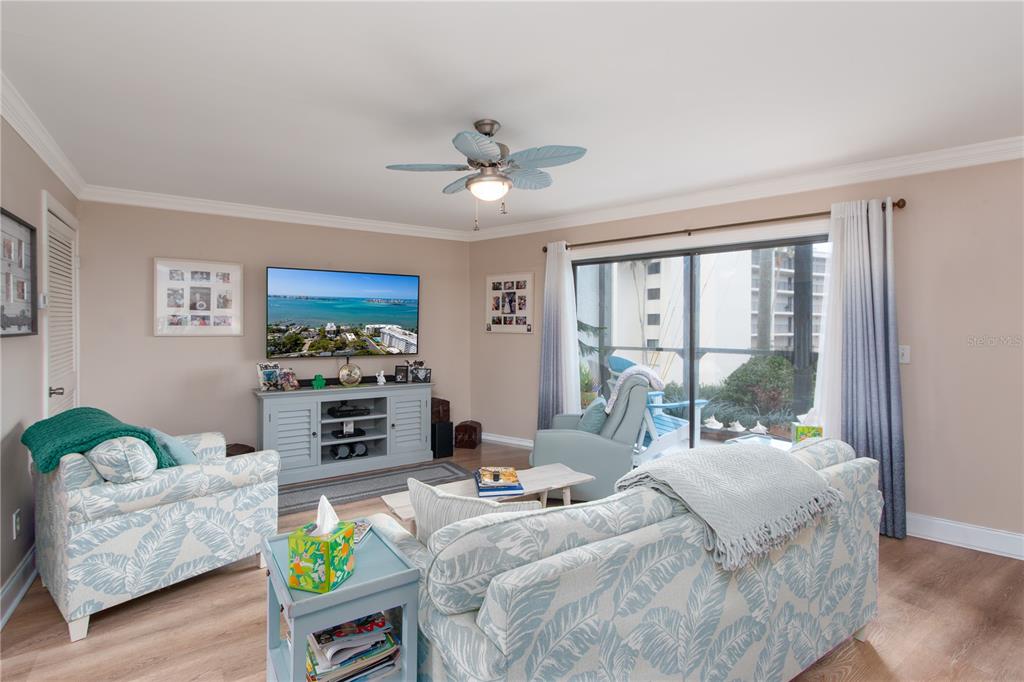 A living room features a patterned sofa, matching armchair, television console, and sliding glass doors — 15 TURNER STREET UNIT 4, CLEARWATER, FL