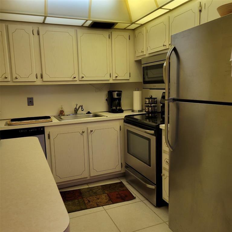 A kitchen features white cabinets, stainless steel appliances, and light-colored tile flooring — 351 Markham P # 351, Deerfield Beach FL 33442, DEERFIELD BEACH, FL