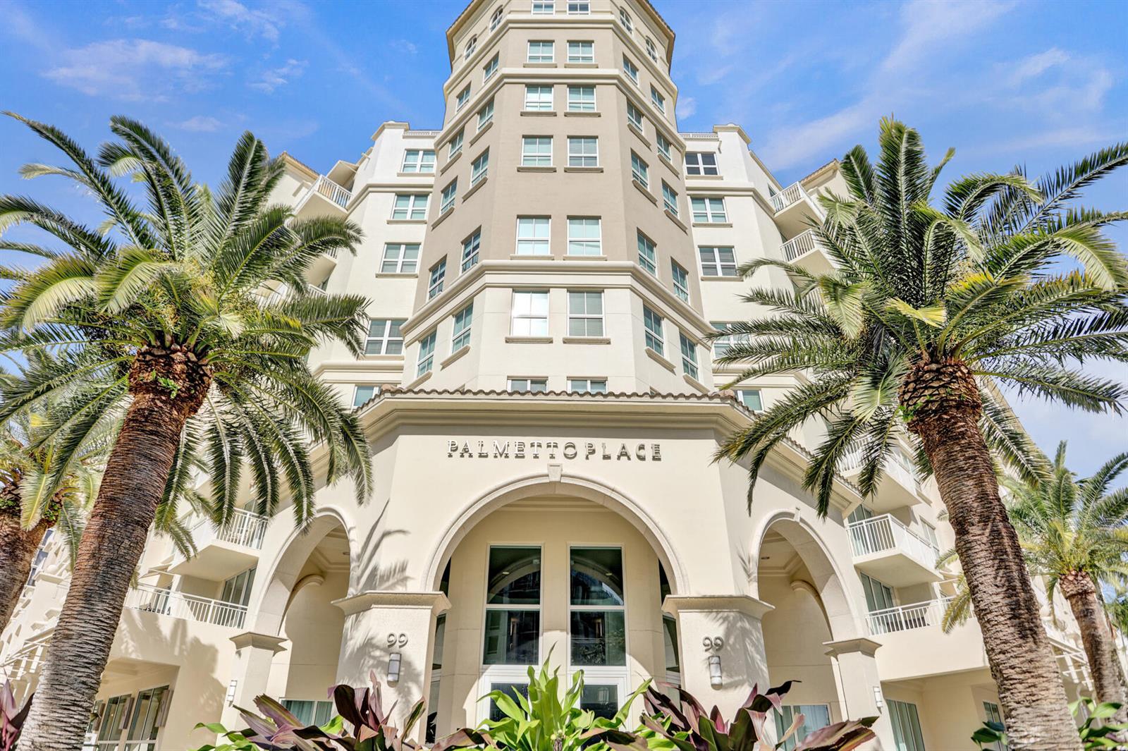 A low-angle exterior view of a multi-story apartment building with palm trees in front — 99 SE Mizner Boulevard # 612, Boca Raton FL 33432, BOCA RATON, FL