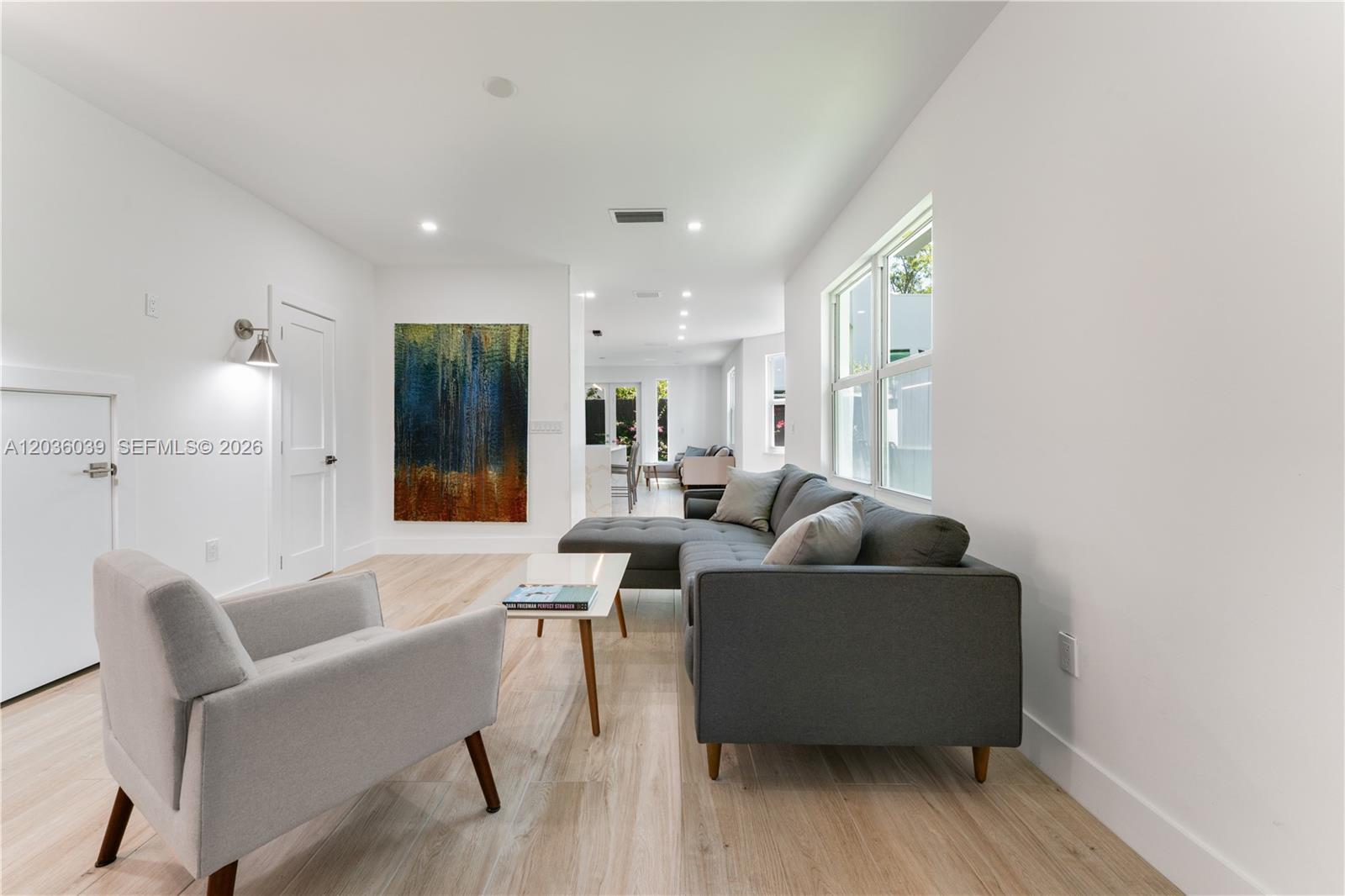 A living room features a grey sectional sofa, a light grey armchair, and wood flooring — 3125 Paola Dr # 15, Miami FL 33133, MIAMI, FL