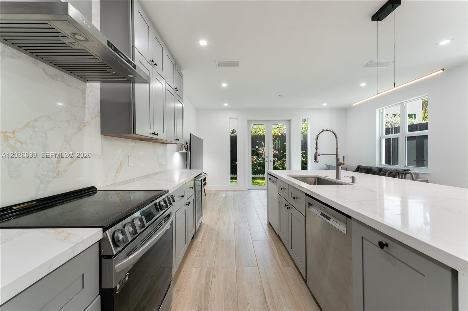A modern kitchen features gray cabinetry, white marble-patterned countertops, and stainless steel appliances — 3125 Paola Dr # 15, Miami FL 33133, MIAMI, FL