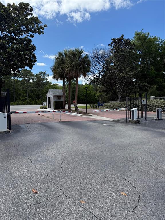 A gated entrance features a security booth, paved driveway, and mature palm trees — 1134 S PINE RIDGE CIRCLE UNIT 1134, SANFORD, FL