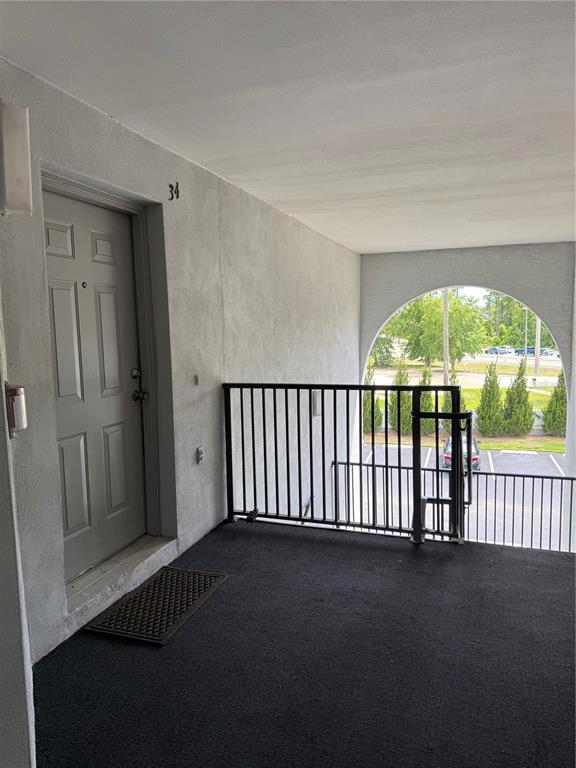 An exterior apartment entryway with a gray door, black railing, and a view of parking — 1134 S PINE RIDGE CIRCLE UNIT 1134, SANFORD, FL