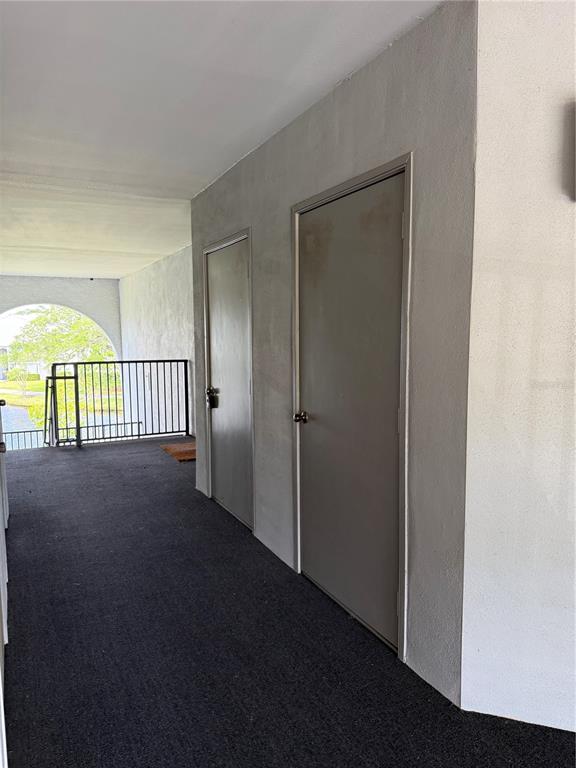 A covered outdoor walkway features two grey doors and a black metal railing — 1134 S PINE RIDGE CIRCLE UNIT 1134, SANFORD, FL