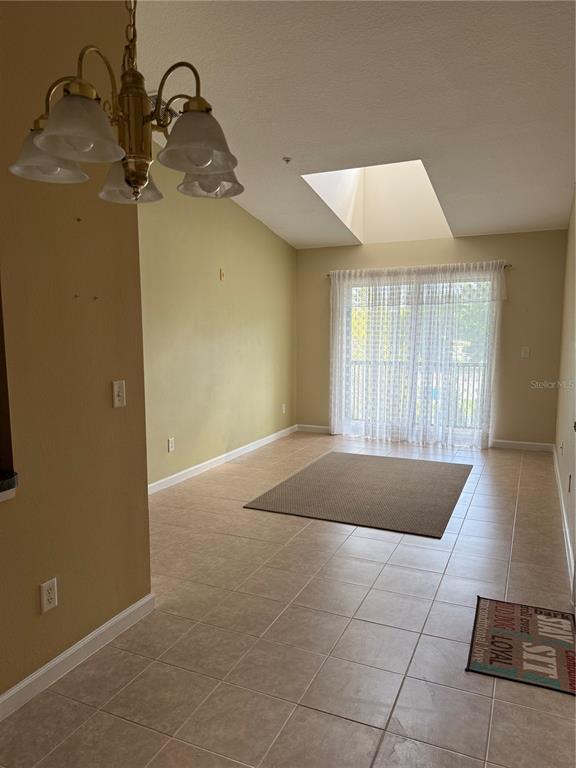 A dining area with tile flooring, a chandelier, a skylight, and sliding glass doors — 1134 S PINE RIDGE CIRCLE UNIT 1134, SANFORD, FL