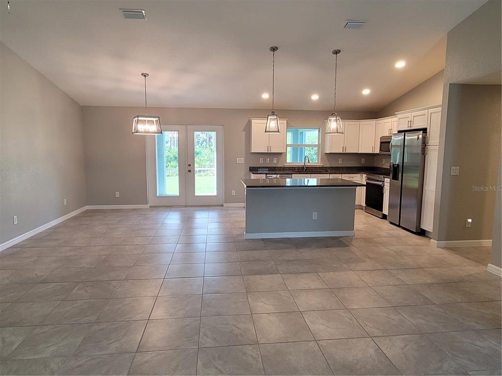 A kitchen with a center island, stainless steel appliances, and tile flooring opens to a patio — 13481 DRYSDALE AVENUE, PORT CHARLOTTE, FL