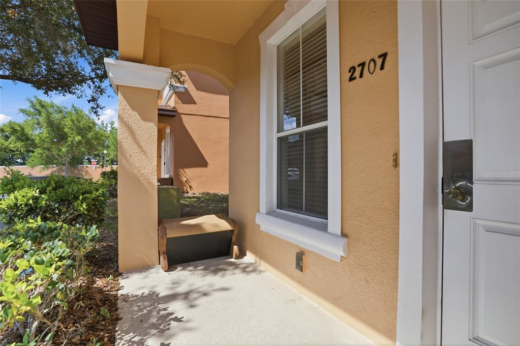 A tan exterior entryway features a white-framed window, a door, and a small bench — 2707 CAMARO DRIVE, KISSIMMEE, FL