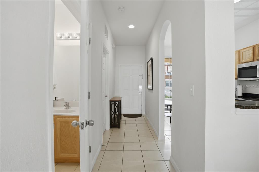 A tiled hallway leads to an entryway with a bathroom on the left and kitchen — 2707 CAMARO DRIVE, KISSIMMEE, FL