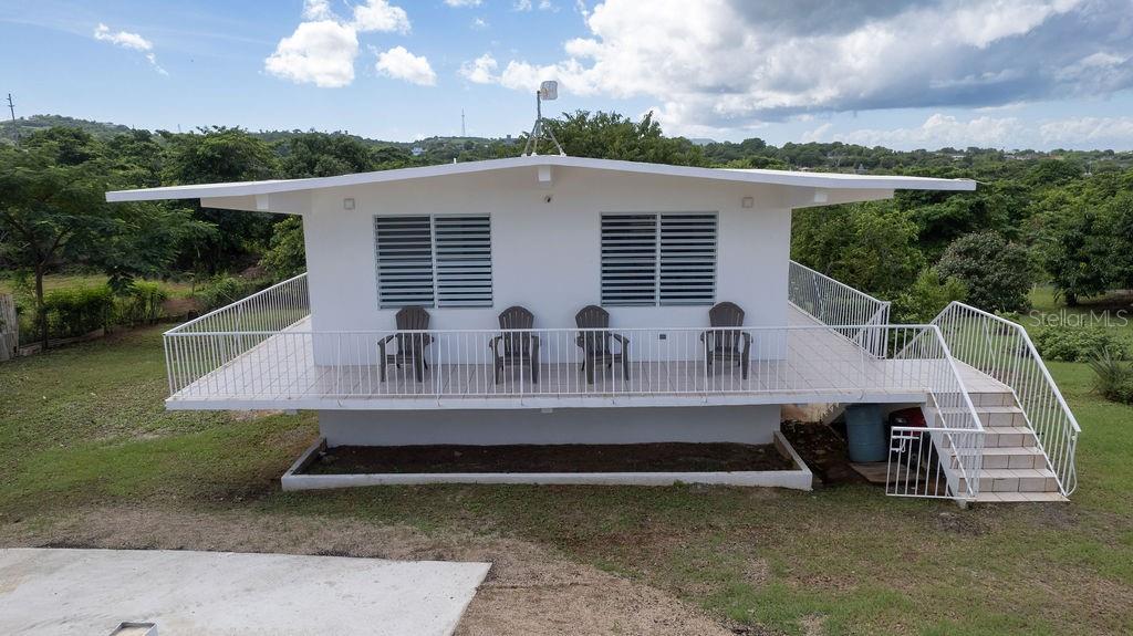 An elevated white house features a wide balcony with four chairs and a staircase — 595 COMM. VILLA BORINQUEN, VIEQUES, PR