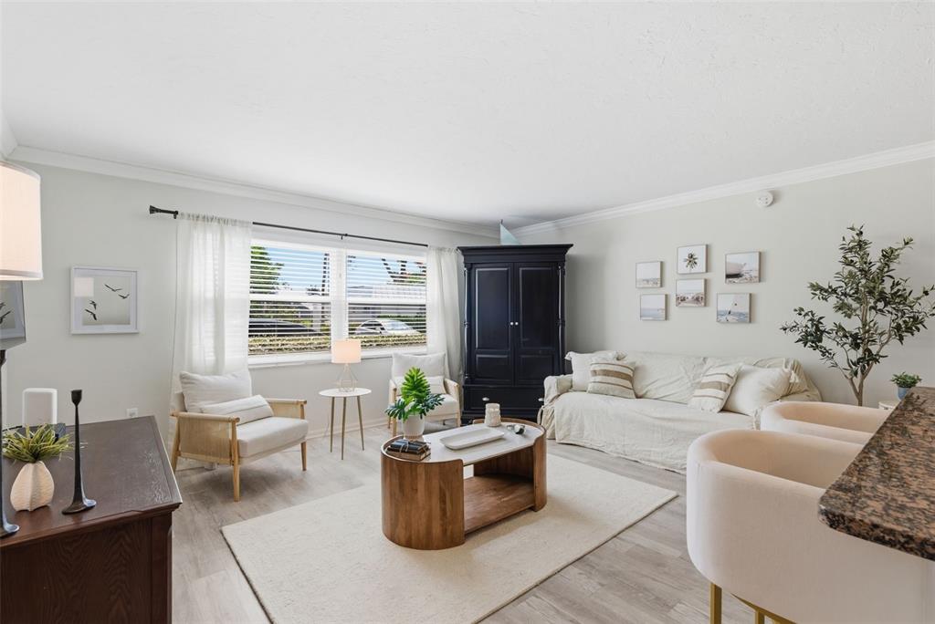 A living room features a white sofa, two armchairs, a wooden coffee table, and an armoire — 5800 HOLLYWOOD BOULEVARD UNIT 214, SARASOTA, FL