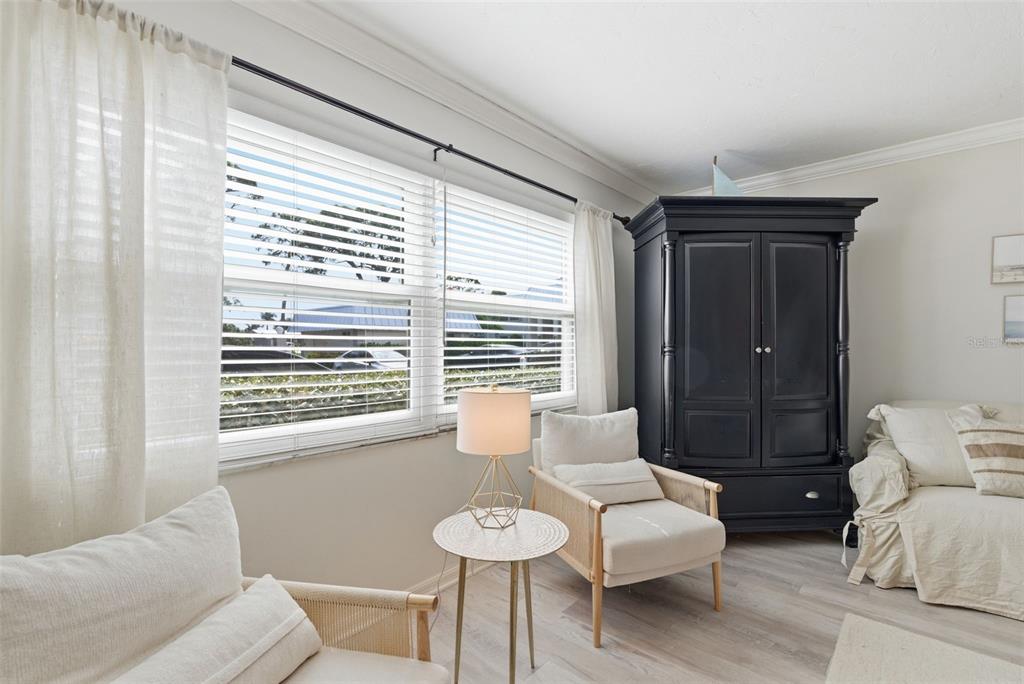 A sunlit room features two light-colored armchairs, a small side table, and a black armoire — 5800 HOLLYWOOD BOULEVARD UNIT 214, SARASOTA, FL
