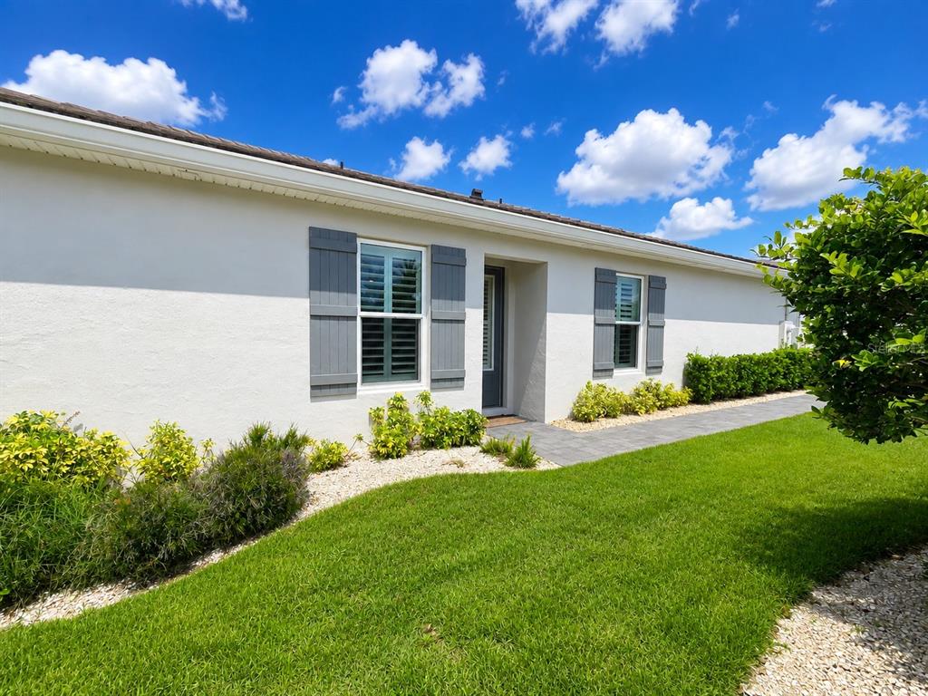 A single-story house with white stucco walls, gray shutters, and a paved walkway — 3079 ISLES WAY, NEW SMYRNA BEACH, FL