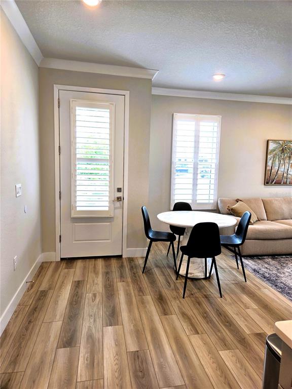 A dining area with a round table, black chairs, wood-look flooring, and a glass-paneled door — 3079 ISLES WAY, NEW SMYRNA BEACH, FL