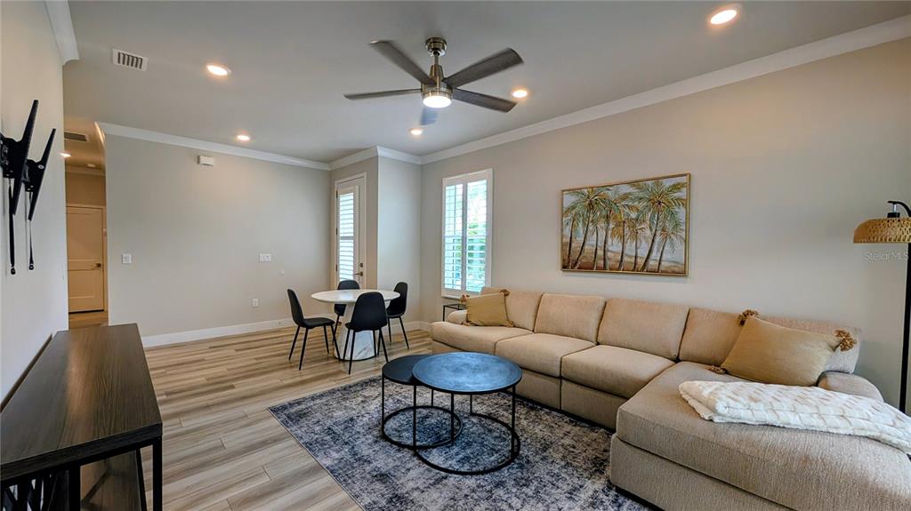 A living room features a sectional sofa, a small dining area, and wood-look flooring — 3079 ISLES WAY, NEW SMYRNA BEACH, FL