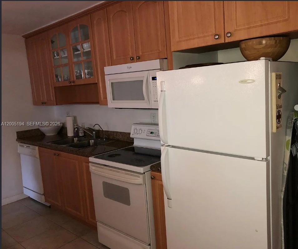 A kitchen features wood cabinets, granite countertops, and white appliances — 7705 SW 86th St # 211, Miami FL 33143, MIAMI, FL