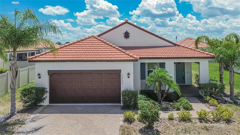 A single-story house with a brown garage door, tile roof, and palm trees in front — 17206 STAR BANKS STREET, WIMAUMA, FL