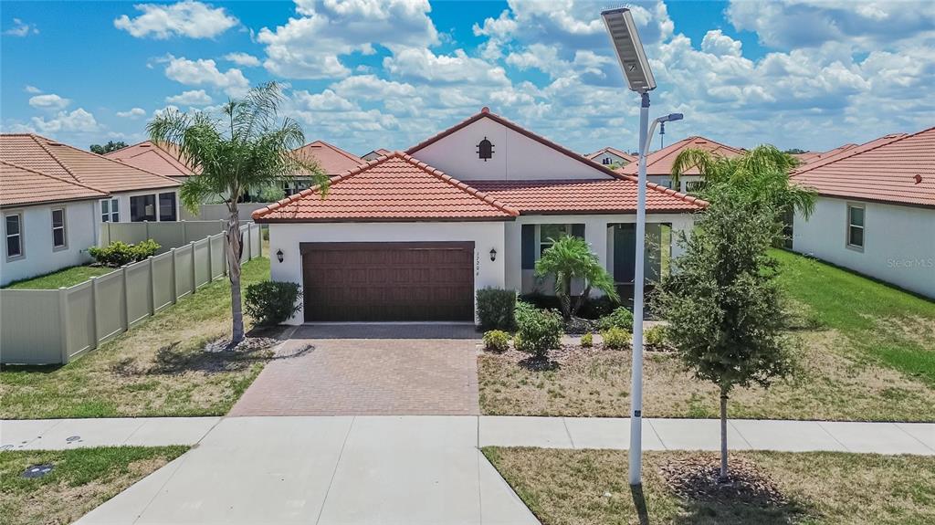 An exterior view of a single-story house with a tile roof and a paved driveway — 17206 STAR BANKS STREET, WIMAUMA, FL