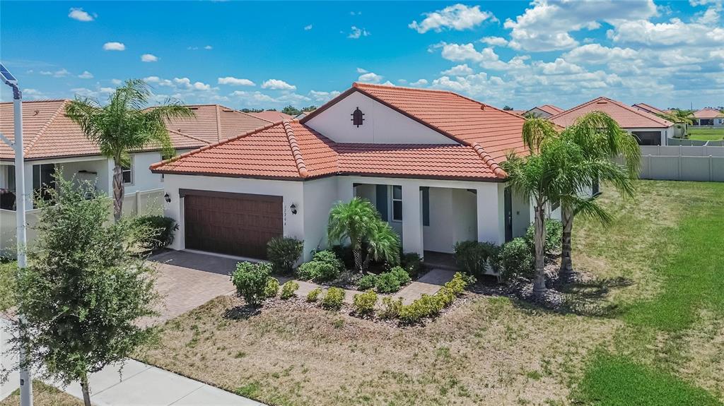A single-story house with a terracotta tile roof, white stucco exterior, and a two-car garage — 17206 STAR BANKS STREET, WIMAUMA, FL