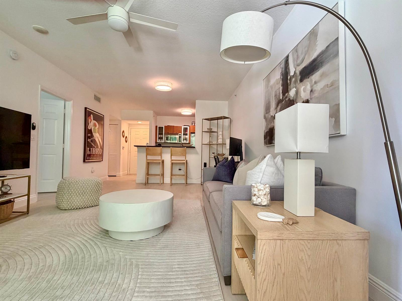 A living room features a grey sofa, a round coffee table, and an open kitchen — 625 Casa Loma Boulevard # 207, Boynton Beach FL 33435, BOYNTON BEACH, FL
