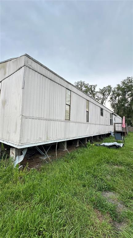 A side view of a weathered, elevated mobile home with metal siding and a small deck — 4422 ROSE STREET, VALRICO, FL