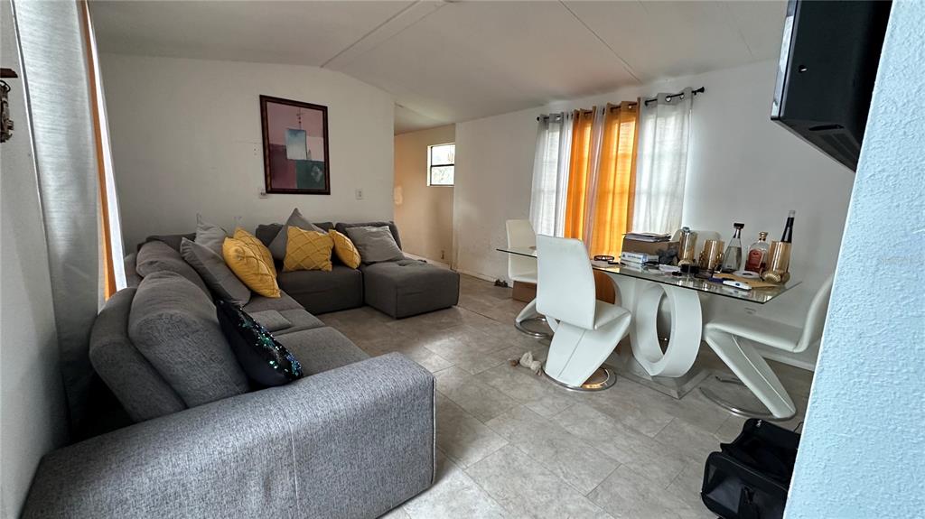 A living and dining area features a gray sectional sofa, a glass table, and tile flooring — 4422 ROSE STREET, VALRICO, FL