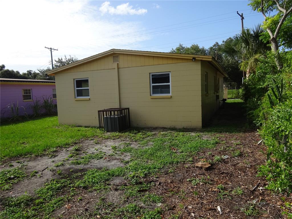 The exterior of a yellow, single-story concrete block house with a fenced air conditioning unit — 4307 E OSBORNE AVENUE, TAMPA, FL