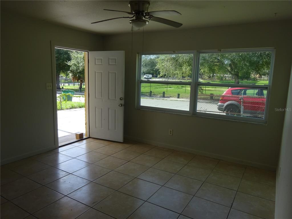 A room with light-colored tile flooring, a ceiling fan, and a door opening to outside — 4307 E OSBORNE AVENUE, TAMPA, FL