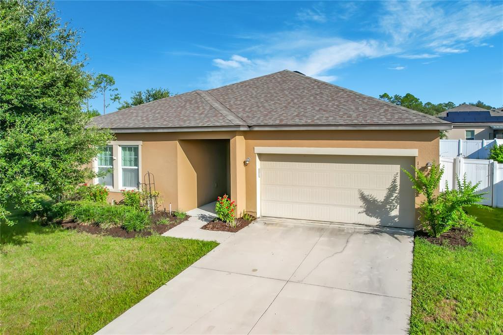 A single-story house with a tan stucco exterior, a two-car garage, and a concrete driveway — 1120 TOBIE ST, LAKE WALES, FL