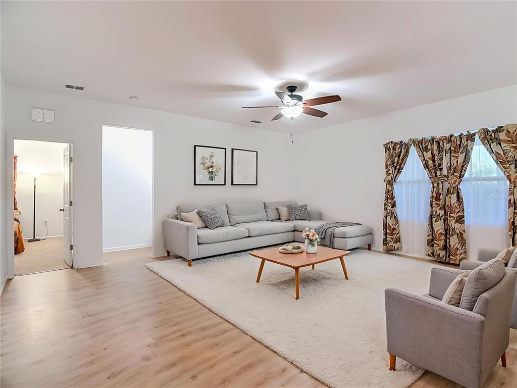 A living room features a light gray sectional sofa, a coffee table, and wood flooring — 1120 TOBIE ST, LAKE WALES, FL