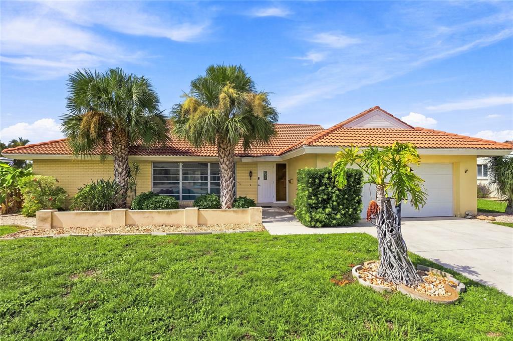 A single-story house with a yellow brick exterior, tile roof, and palm trees in front — 425 BELVEDERE COURT, PUNTA GORDA, FL