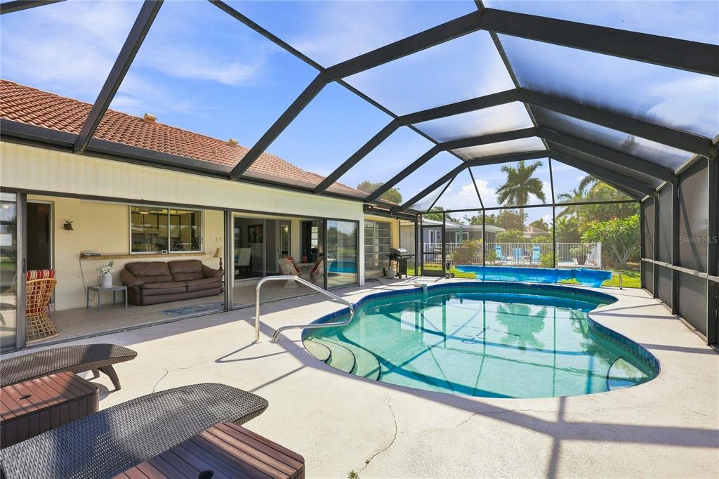 A screened-in patio features a swimming pool, lounge chairs, and sliding glass doors to the house — 425 BELVEDERE COURT, PUNTA GORDA, FL