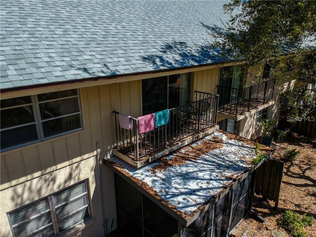 An elevated view of a building exterior featuring a balcony with towels and a screened patio — 525 PARKDALE UNIT 525, VENICE, FL