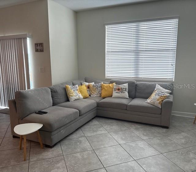 A gray sectional sofa sits on a tiled floor in a room with a large window — 15054 HARRINGTON COVE DRIVE, ORLANDO, FL