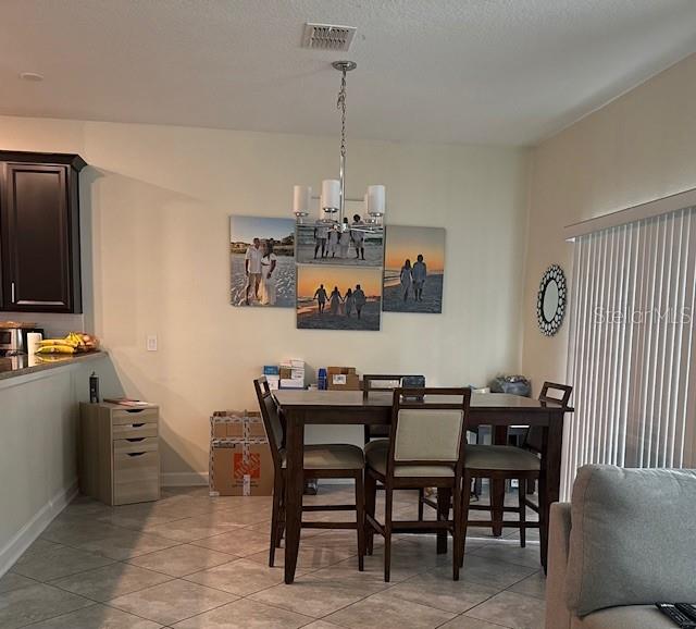 A dining area features a wooden table, four chairs, a chandelier, and wall-mounted photo canvases — 15054 HARRINGTON COVE DRIVE, ORLANDO, FL