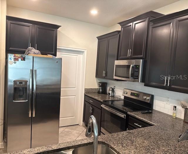 A kitchen features dark wood cabinets, stainless steel appliances, and granite countertops — 15054 HARRINGTON COVE DRIVE, ORLANDO, FL