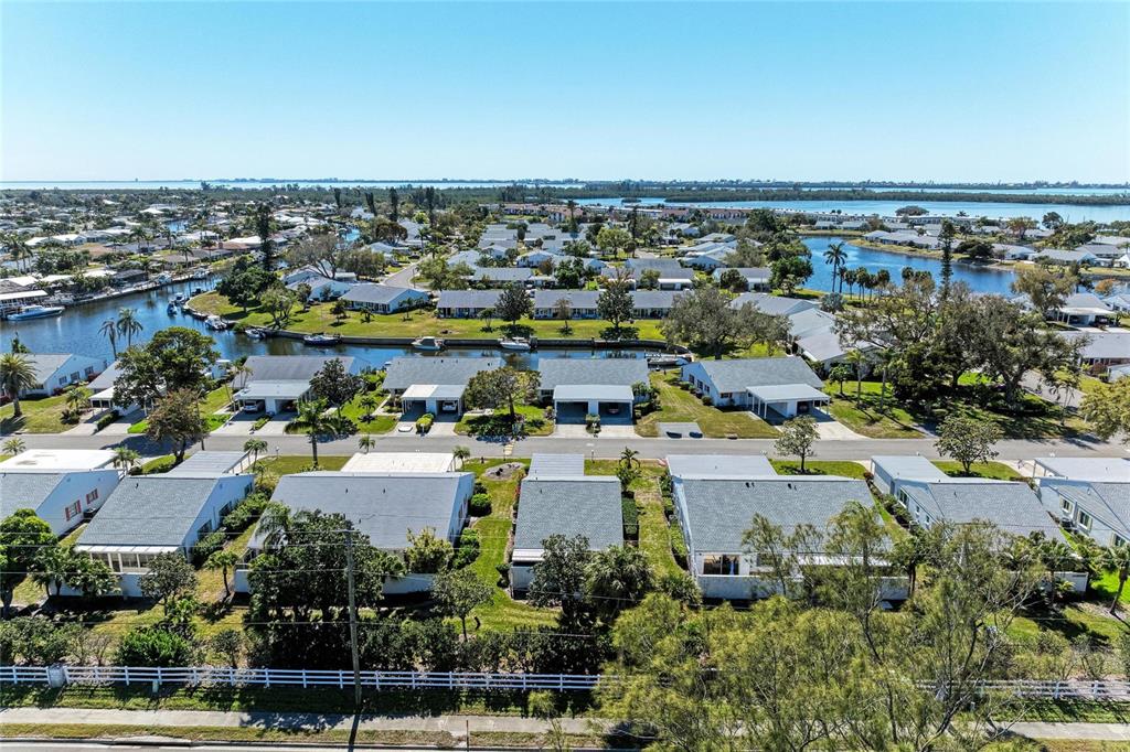 An aerial view shows a residential neighborhood with houses, a canal, and surrounding vegetation — 9417 KINGSTON DRIVE UNIT 9417, BRADENTON, FL