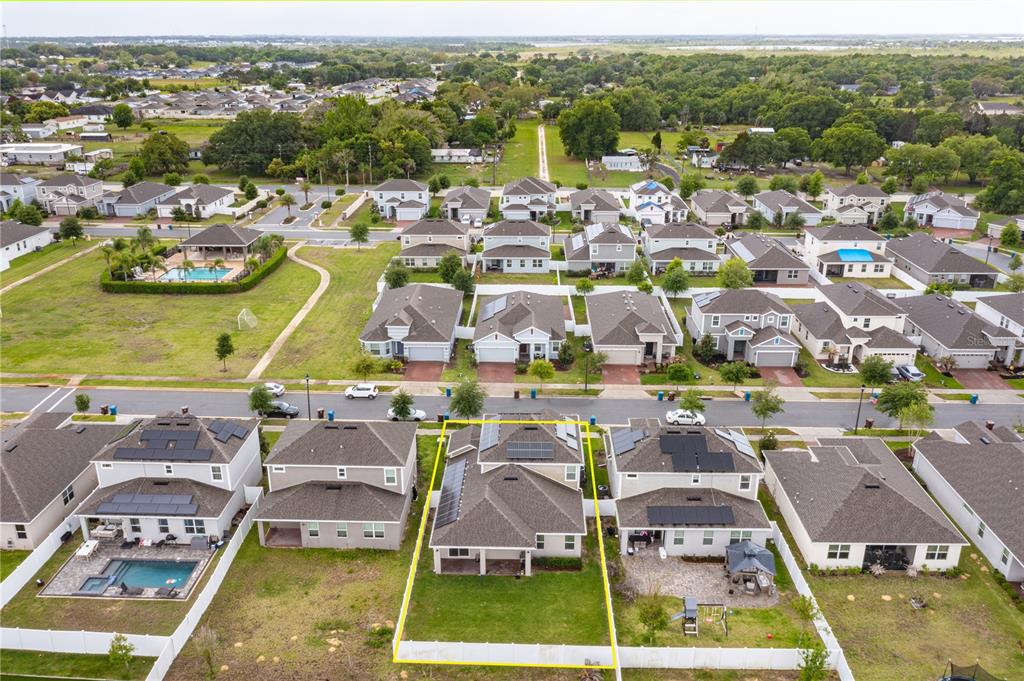 An aerial view shows a suburban neighborhood with houses featuring solar panels and backyards — 1324 YORKDALE ROAD, DAVENPORT, FL