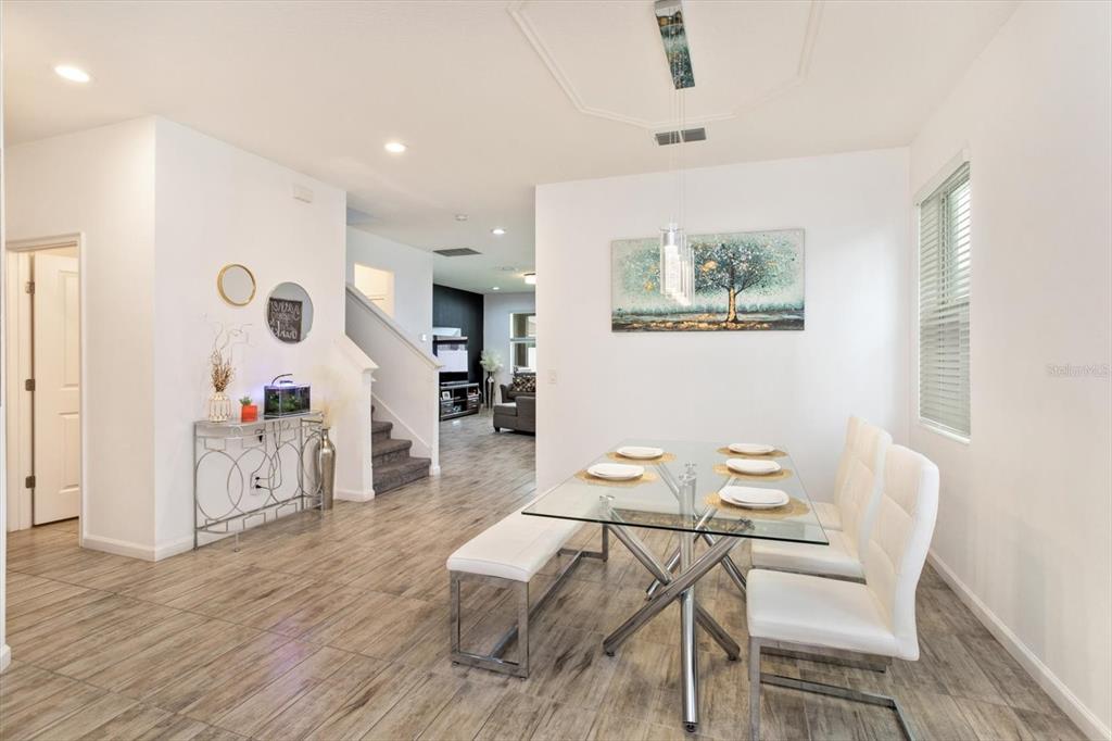 A dining area features a glass table, white chairs, a bench, and wood-look tile flooring — 1324 YORKDALE ROAD, DAVENPORT, FL