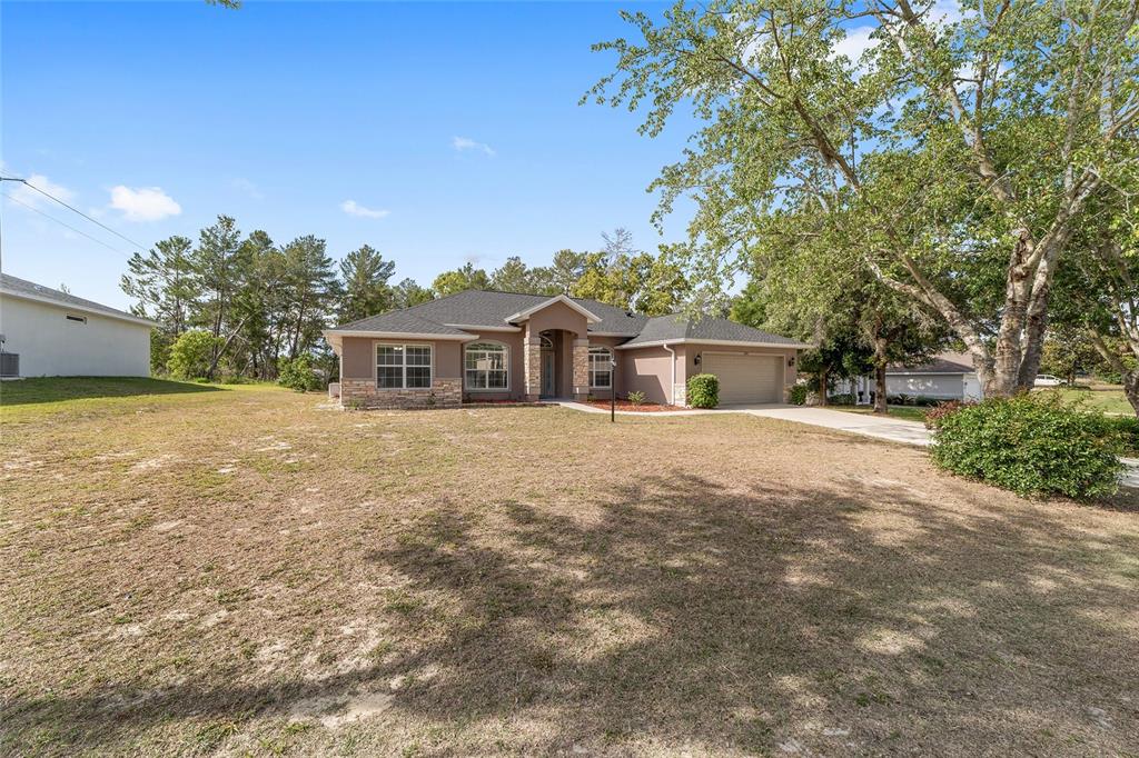 A single-story house with a stone facade, a two-car garage, and a large front yard — 5061 SW 109TH LOOP, OCALA, FL