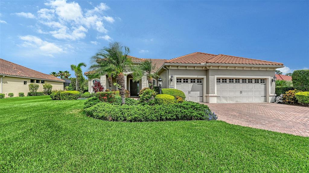 A single-story house with a tile roof, a three-car garage, and a landscaped front yard — 8215 LARKSPUR CIRCLE, SARASOTA, FL