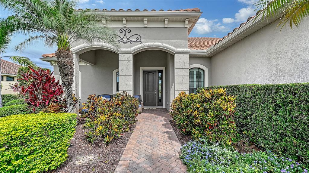 The exterior of a house features a brick walkway leading to a covered front entrance — 8215 LARKSPUR CIRCLE, SARASOTA, FL