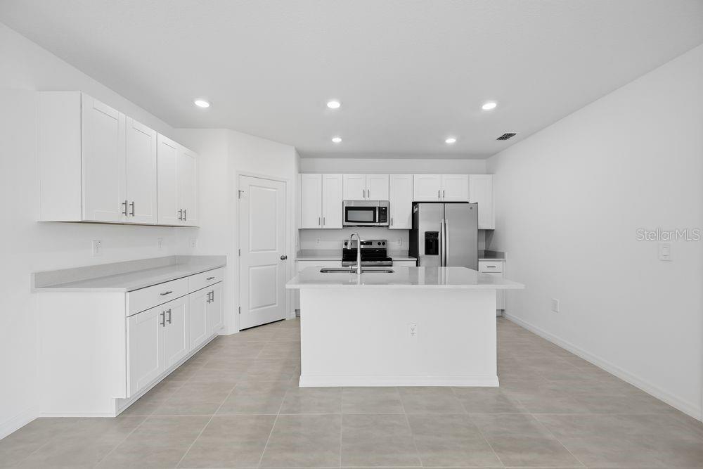A modern kitchen features white cabinets, stainless steel appliances, and a central island — 12423 WHISK COURT, HUDSON, FL