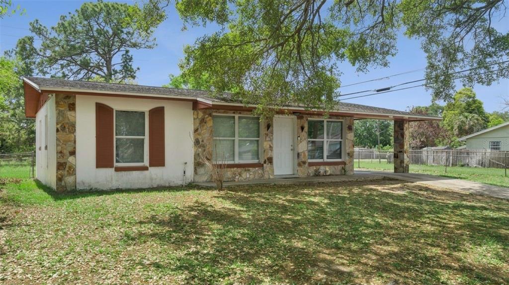 A single-story house with a stone facade, white walls, brown shutters, and an attached carport — 4366 KIRKLAND BOULEVARD, ORLANDO, FL
