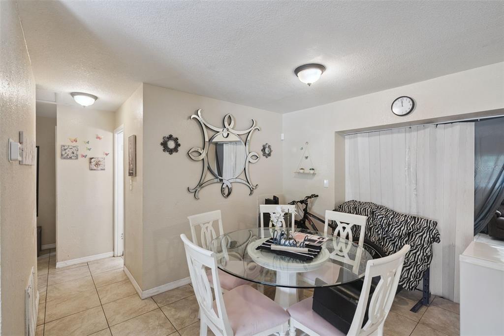 A dining area features a glass-topped table, white chairs, a decorative mirror, and tile flooring — 4366 KIRKLAND BOULEVARD, ORLANDO, FL