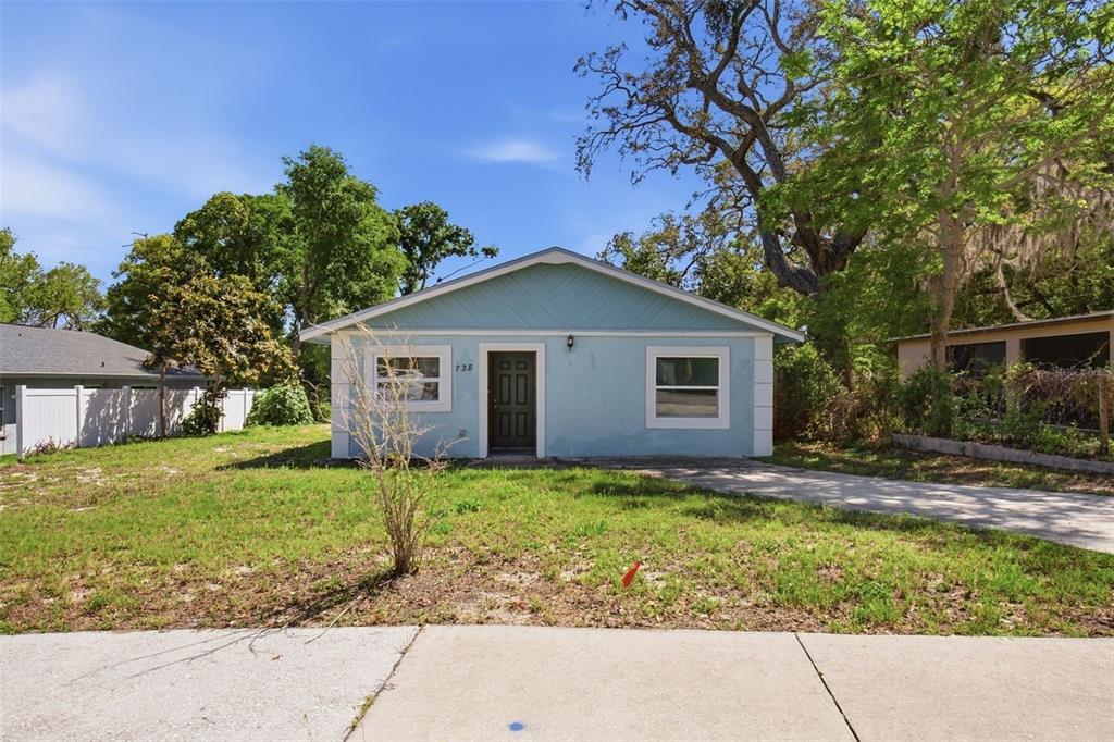 A light blue single-story house with a dark front door sits on a grassy lot — 728 E SPRUCE STREET, TARPON SPRINGS, FL