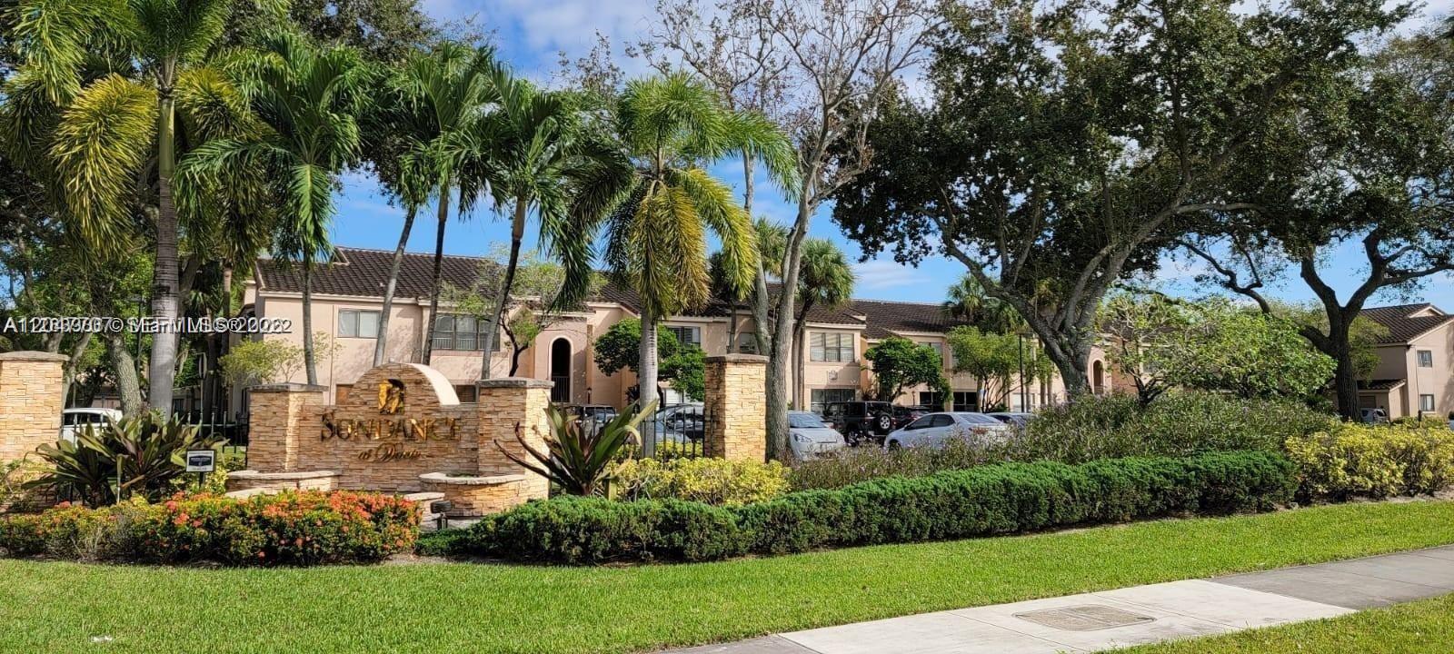 The exterior of a residential complex features a stone entrance sign, palm trees, and landscaping — 2846 S University Dr # 4308, Davie FL 33328, DAVIE, FL