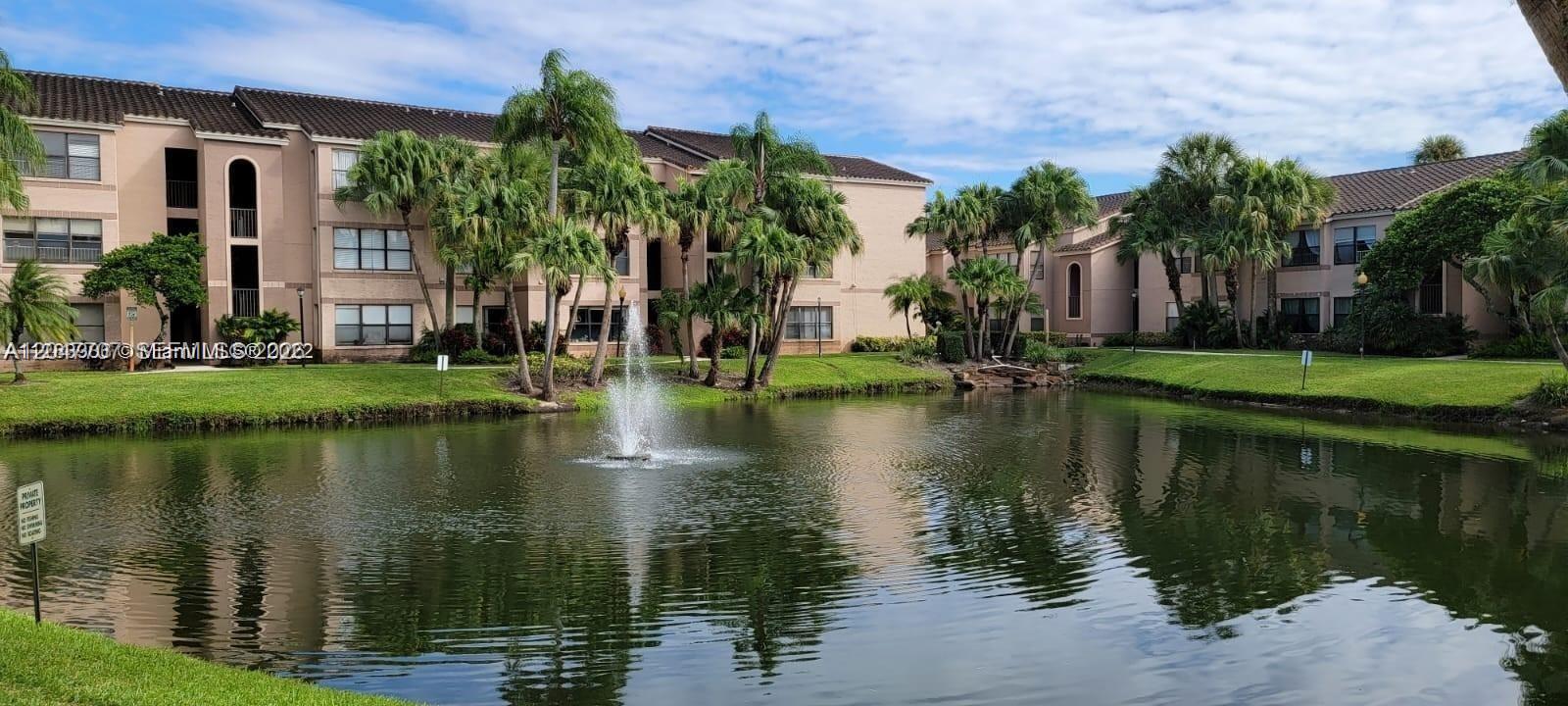 A multi-story apartment complex overlooks a pond with a central fountain and palm trees — 2846 S University Dr # 4308, Davie FL 33328, DAVIE, FL