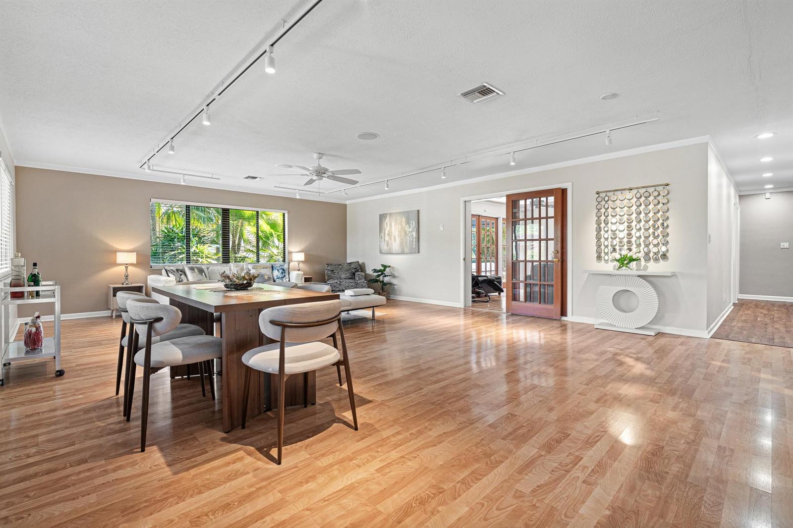 A dining area with a wooden table and chairs sits in a spacious, open-concept living room — 708 NW 6th Drive, Boca Raton FL 33486, BOCA RATON, FL